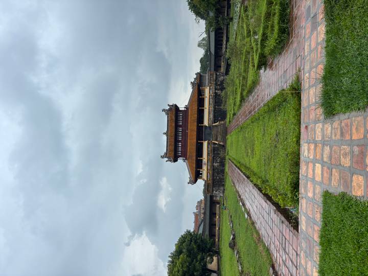 Historic wooden gatehouse of the Imperial City in Hue framed by stone walls under a grey sky