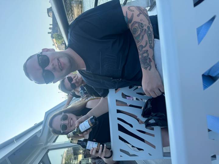 Casual candid of friends holding drinks on an open boat during daylight.