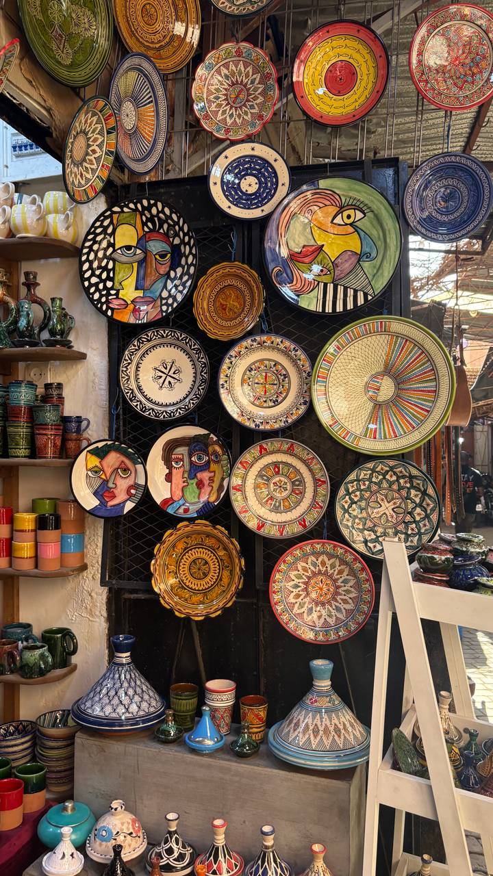 Colorful hand-painted Moroccan ceramic plates and bowls arranged artistically on a market wall.
