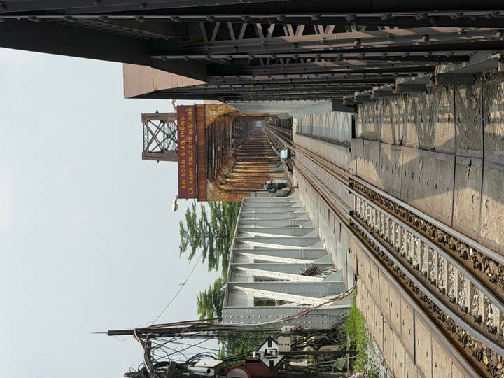 Perspective view down the Long Bien railway bridge in Hanoi with tracks stretching into the distance.