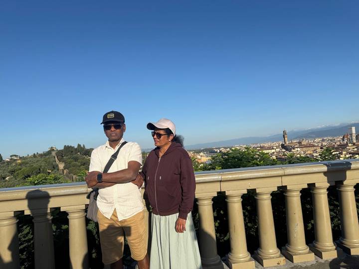Couple posing at panoramic terrace overlooking Florence and its Duomo under clear blue sky.