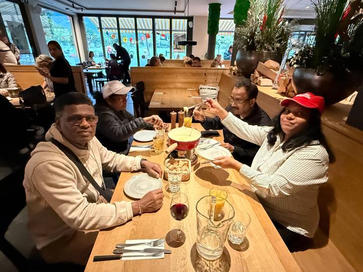 Friends sharing a cheese fondue meal at a cozy restaurant table.