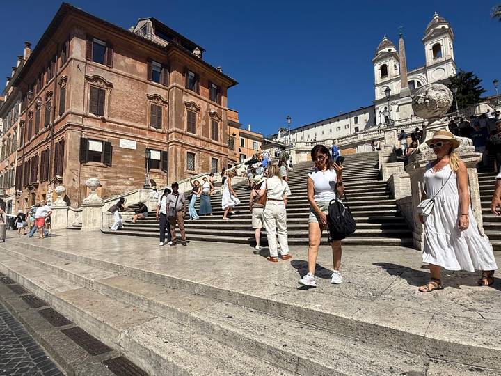 Tourists strolling and posing on the lower terrace of the Spanish Steps in Rome.
