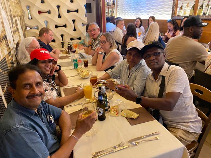 Large group of diners raising drinks around a long restaurant table.