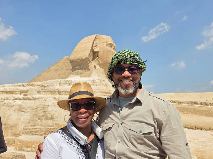 Smiling travelers posing before the Great Sphinx on a bright day.