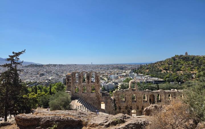 Panoramic view over Athens with the ancient Odeon of Herodes Atticus in the foreground and city stretching to the sea.