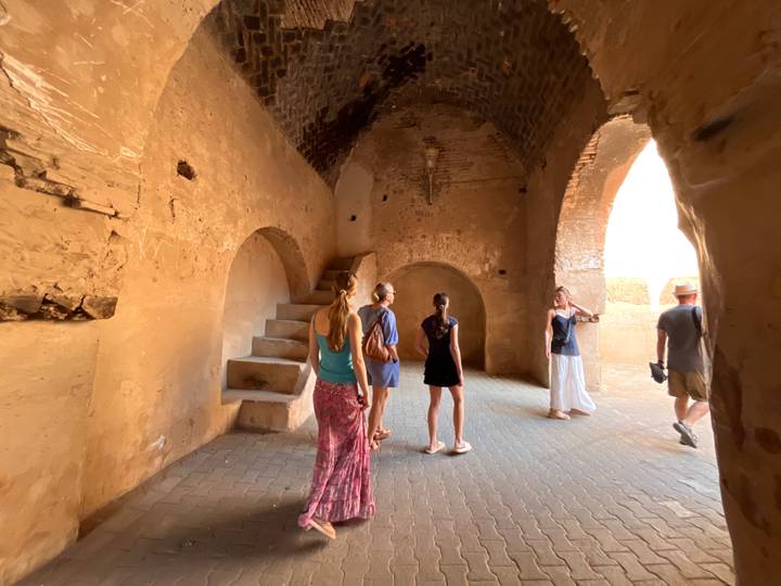 Visitors explore the vaulted interior of an earthen fort with arched ceilings and narrow staircases.