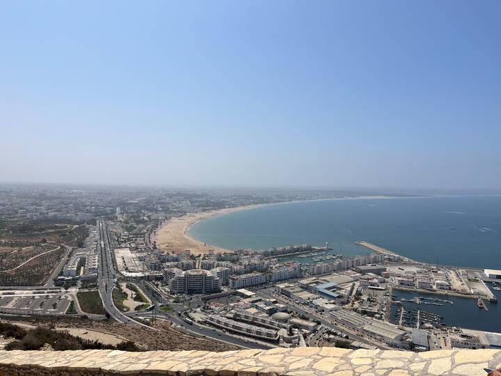 Aerial panorama of Agadir’s curving beach, marina and city stretching along the Atlantic coast.