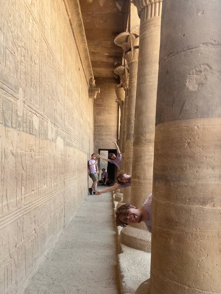 Playful composite shot of a traveller appearing multiple times between ancient stone columns engraved with hieroglyphs.