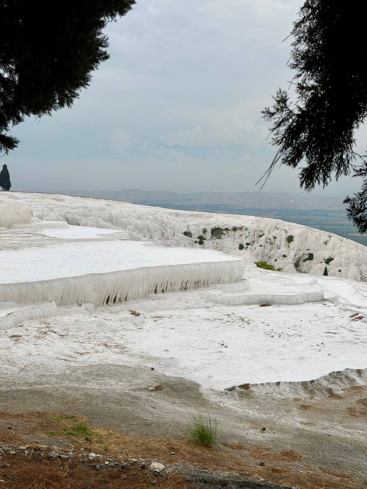 White travertine terraces of Pamukkale gleaming against a hazy Anatolian plain.
