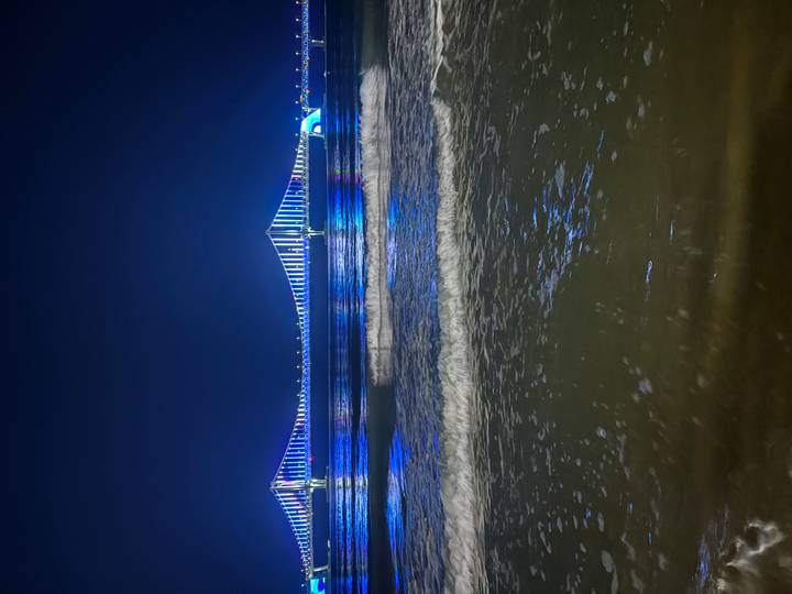 Illuminated Gwangan Bridge spanning over gentle waves at night in Busan.