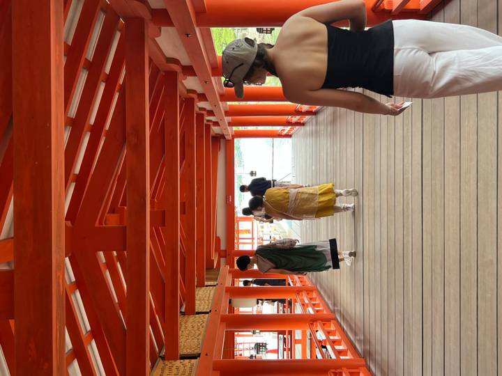 Visitors walk along the vivid vermilion timber corridors of a coastal Shinto shrine.