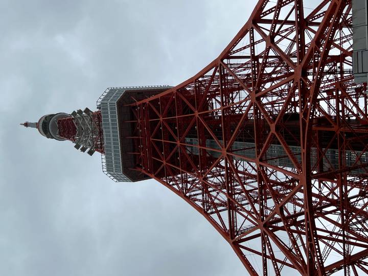 Low-angle view of the red and white Tokyo Tower against a grey sky.