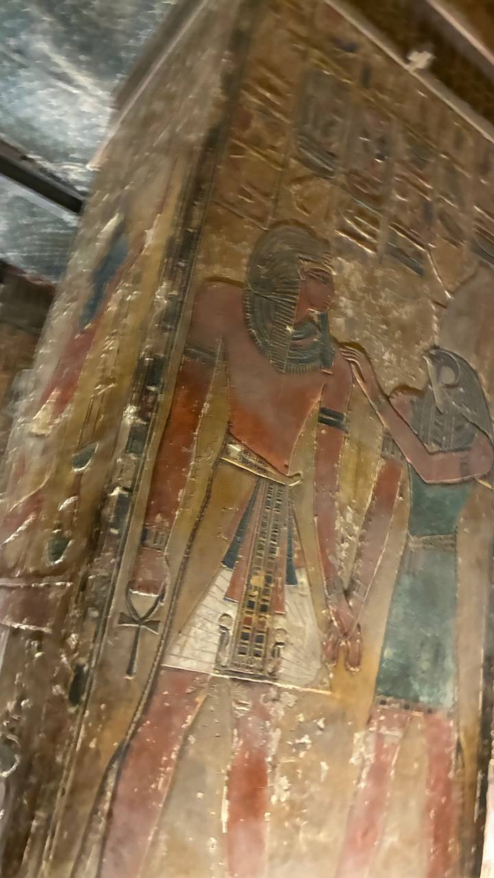 Close-up of a painted Ancient Egyptian relief showing two deities in faded colours
