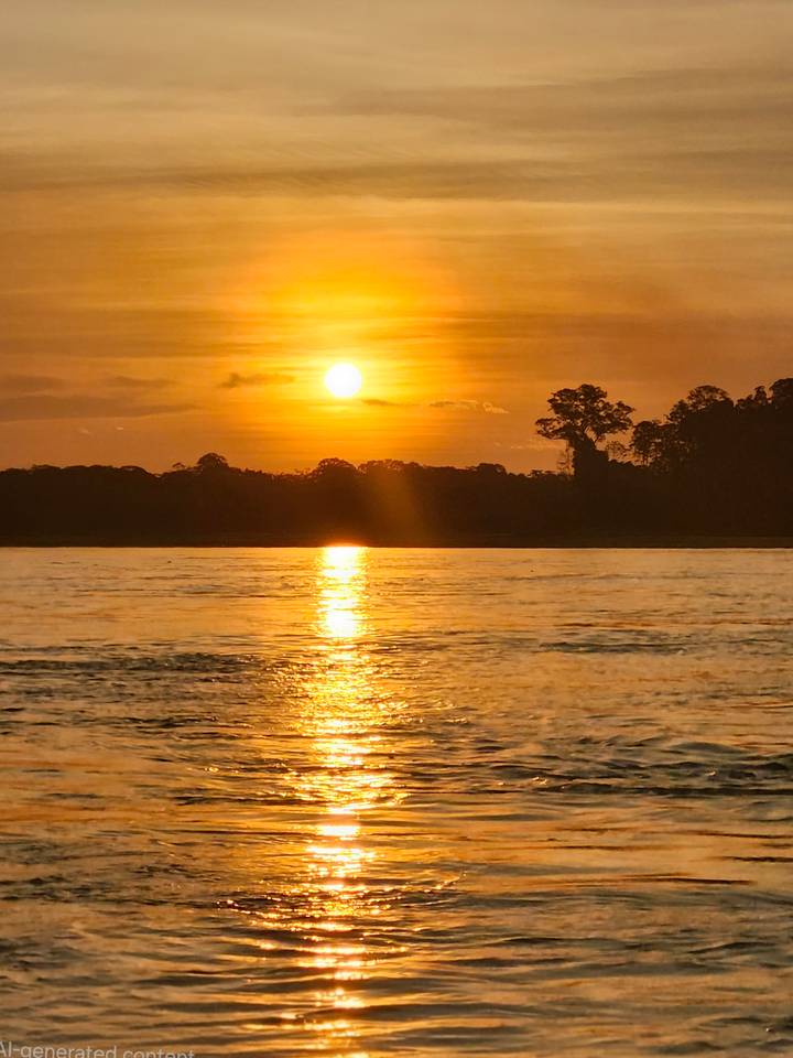 Fiery orange sunset mirrored in the broad Amazon river with dark jungle silhouette on the horizon