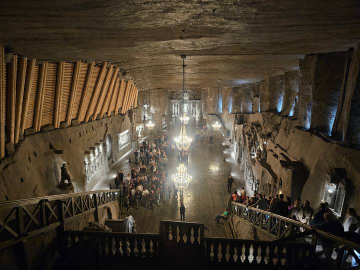 Illuminated chandelier hall carved from salt deep within the Wieliczka Salt Mine, bustling with visitors.