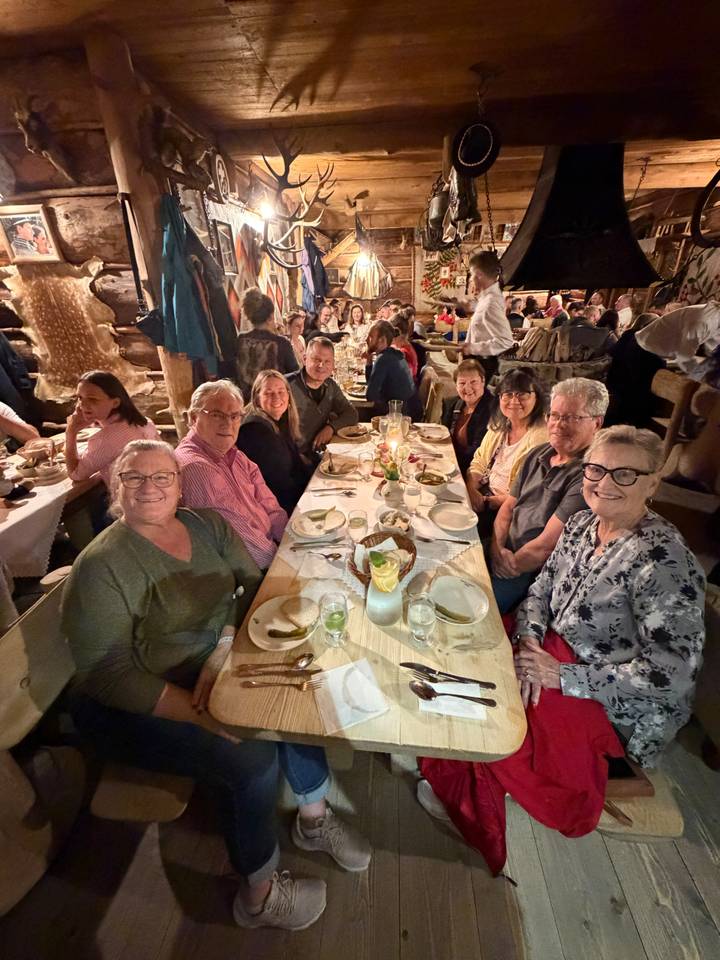 Another angle showing a group of travelers seated for dinner in a lively restaurant setting.