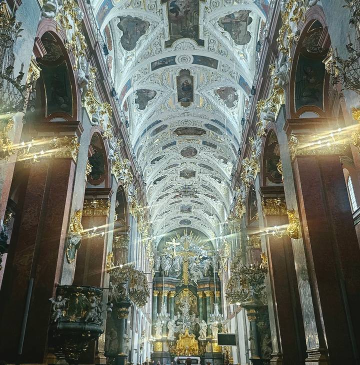 Ornate baroque church nave with gilded columns, marble arches and dramatic light streaks.