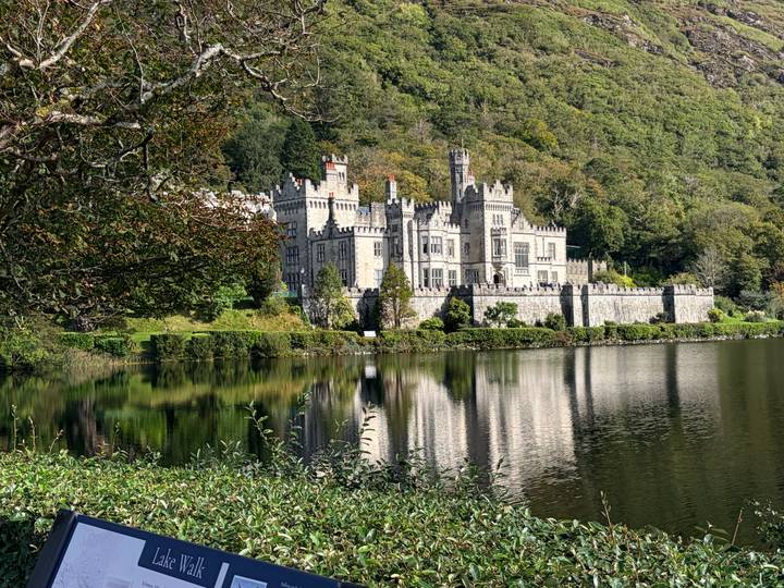 Picturesque Kylemore Abbey reflected in a calm lake surrounded by lush green hills in Connemara.