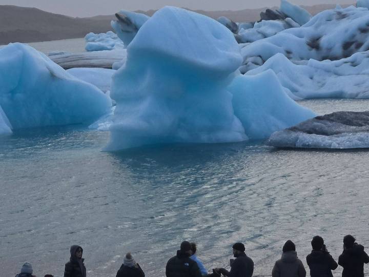Blue icebergs of varying shapes float in the still waters of a glacial lagoon.
