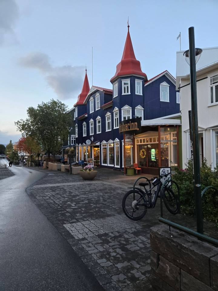 Charming main street of Akureyri lined with colourful wooden buildings, shops and bicycles at dusk.