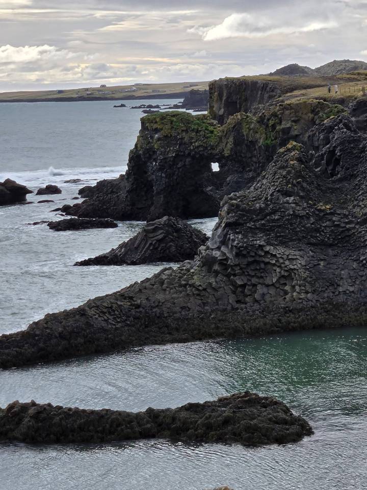 Jagged basalt sea cliffs and arches along the rugged coastline near Arnarstapi village.