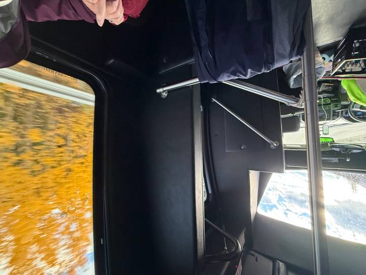 Side view inside a moving bus with blurred autumn foliage rushing past the window.