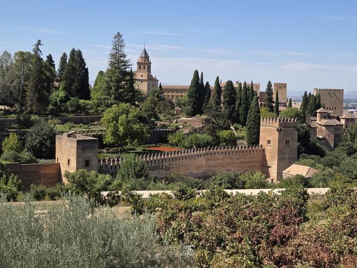 Panoramic view of fortified walls and lush gardens of the Alhambra complex.