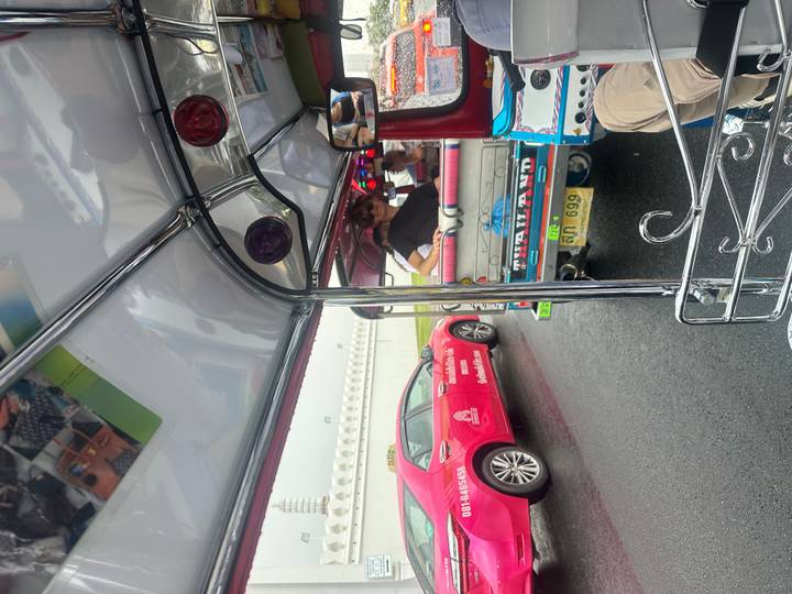 Passengers ride in colourful tuk-tuks amid busy Bangkok traffic after a rain shower.