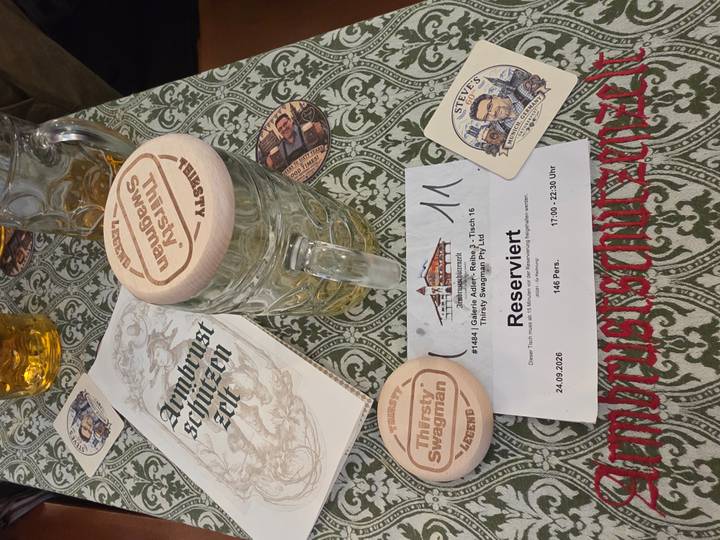 Beer stein with coaster and reservation slip on a wooden table at Oktoberfest.