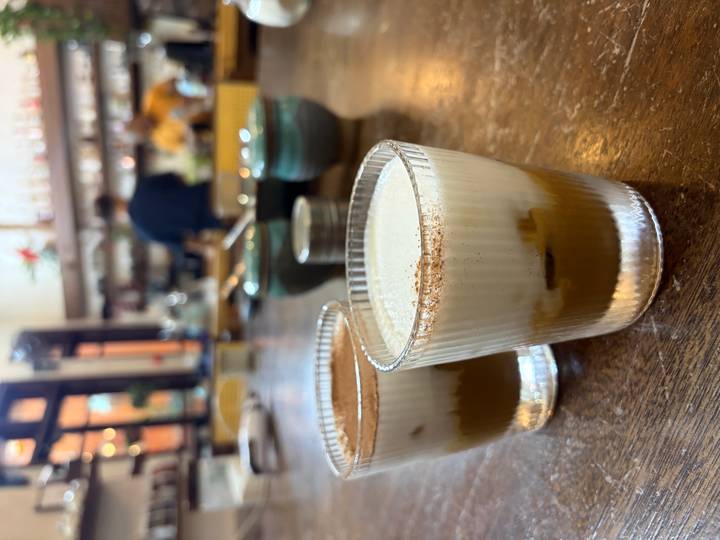 Close-up of two layered Vietnamese egg coffees on a rustic wooden café table.