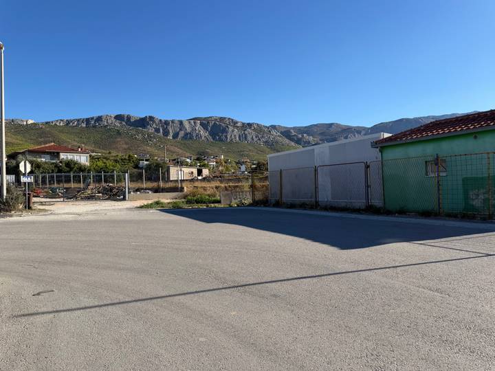 Rural industrial lot with distant mountain ridge under clear sky.