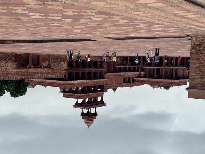 Large sandstone palace courtyard with scattered tourists exploring.