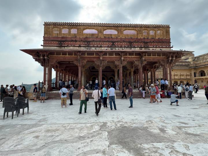 Crowded courtyard inside Amber Fort with ornate columns and tourists.