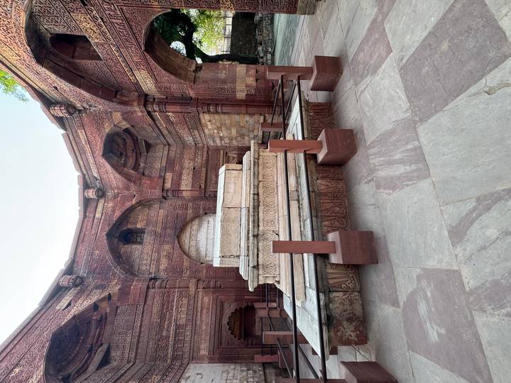 Intricately carved red sandstone tomb inside the Qutub complex.