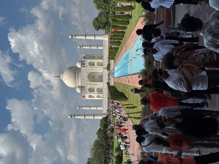 Iconic frontal view of the Taj Mahal with reflecting pool and large crowds.