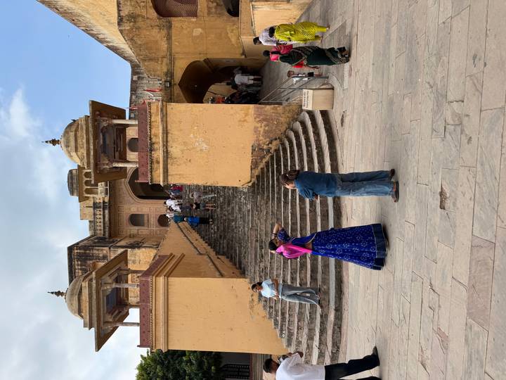 Visitors climbing wide stone staircase to Amber Fort entrance towers.