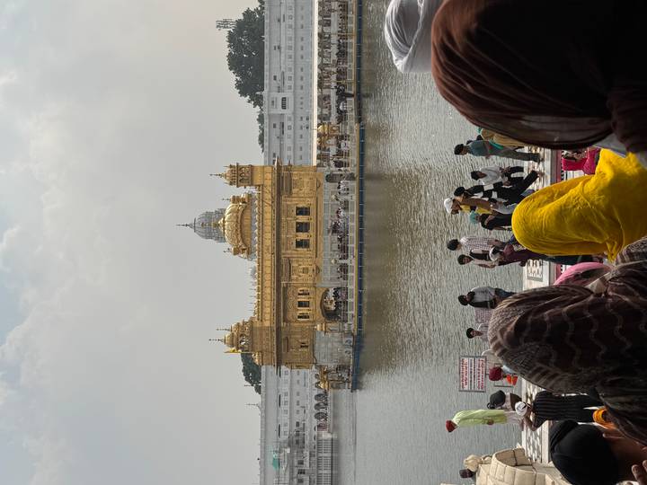 Golden Temple shimmering across the holy pool with crowds of worshippers in colourful headscarves in the foreground.