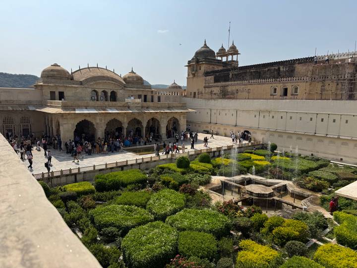 Elevated view of Amber Fort’s lush Mughal garden courtyard bustling with visitors and fountains.