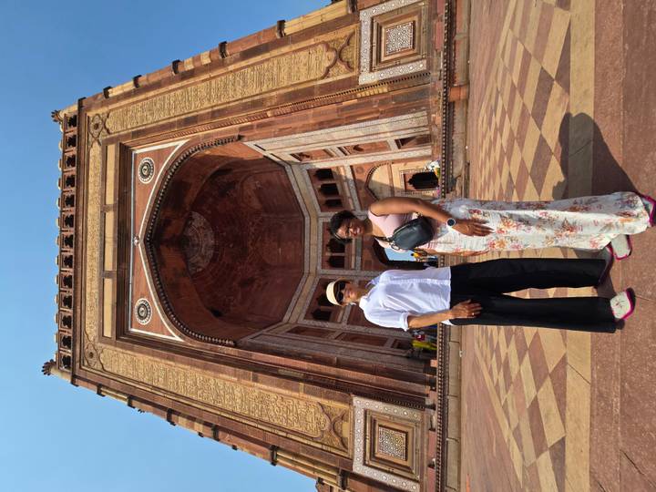 Two women stand below the towering Buland Darwaza gate at Fatehpur Sikri.