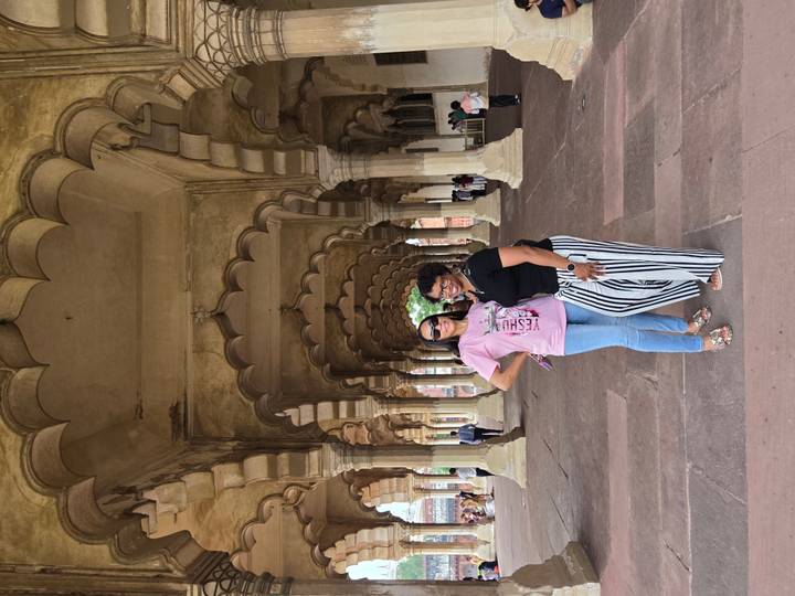 Friends pose under a series of scalloped arches in a grand Mughal hall.