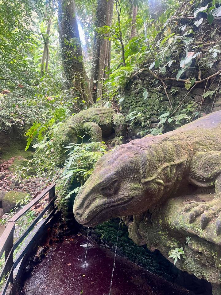 Moss-covered reptile sculptures blend into dense forest foliage.
