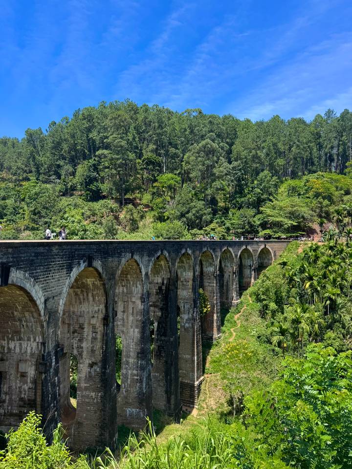 Historic Nine-Arch Bridge spans a lush valley surrounded by dense forest.