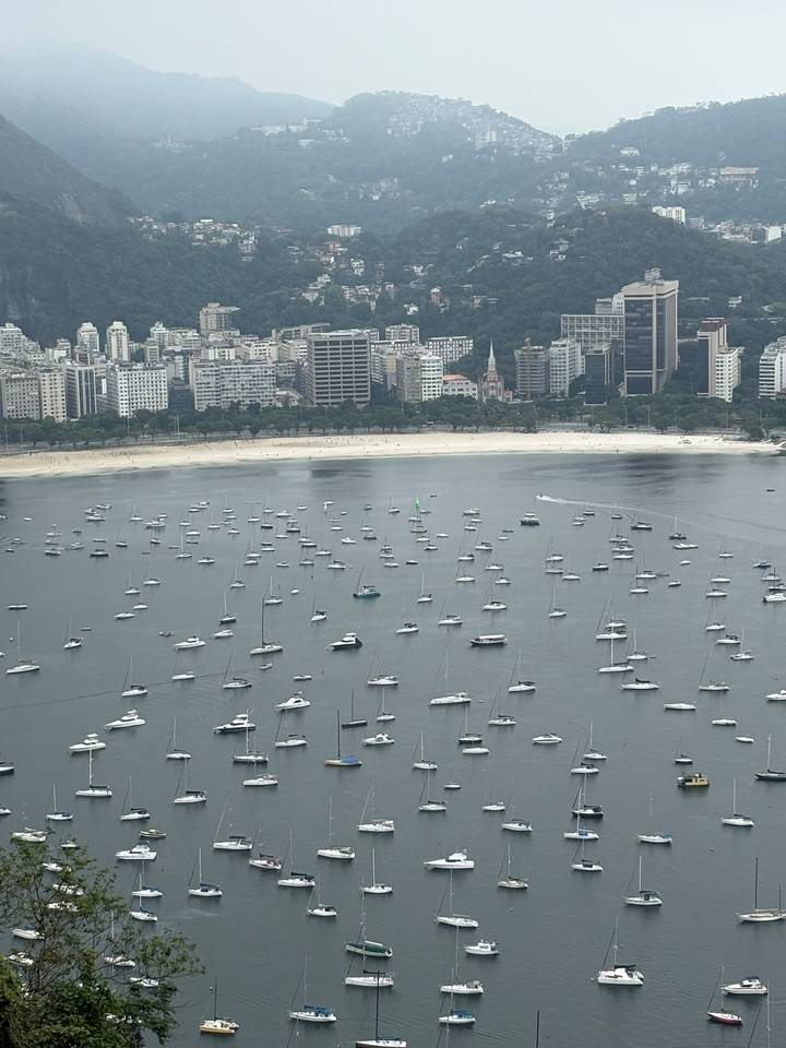 High vantage of Botafogo Bay peppered with anchored boats against Rio skyline.