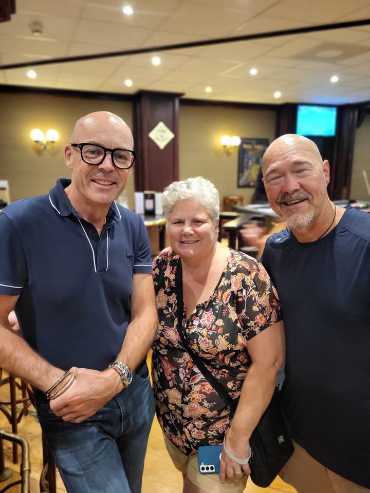 Casual indoor snapshot of three friends smiling for the camera.