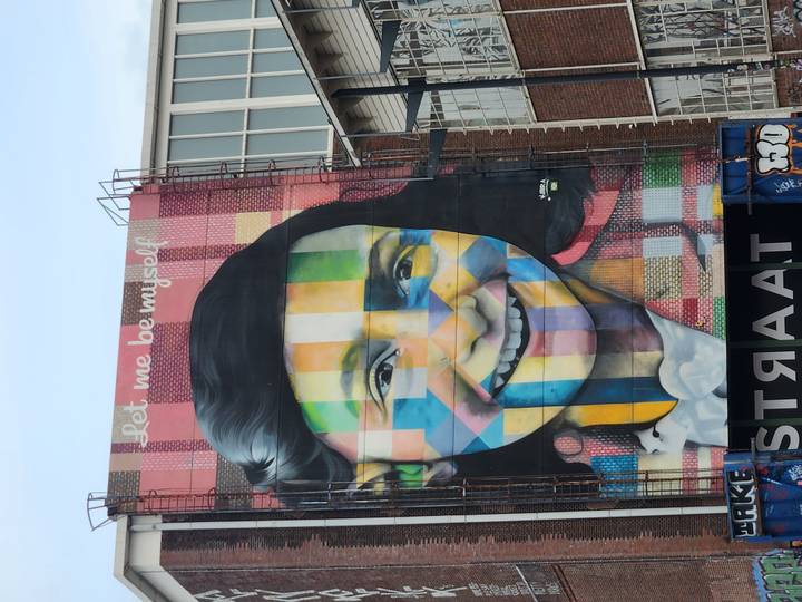 Colorful mural of Anne Frank on a tall building at STRAAT museum.