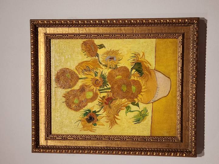 Vincent van Gogh's 'Sunflowers' painting framed in gold against a gallery wall.