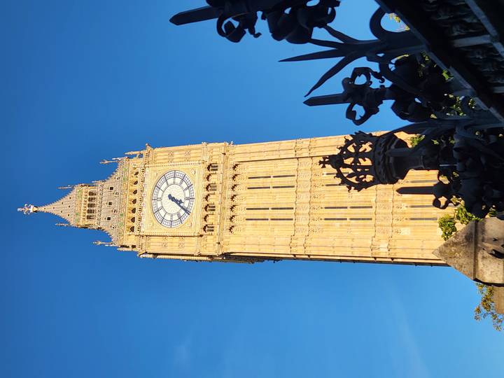 Iconic Elizabeth Tower with its clock face gleaming against a deep blue sky during warm evening light.