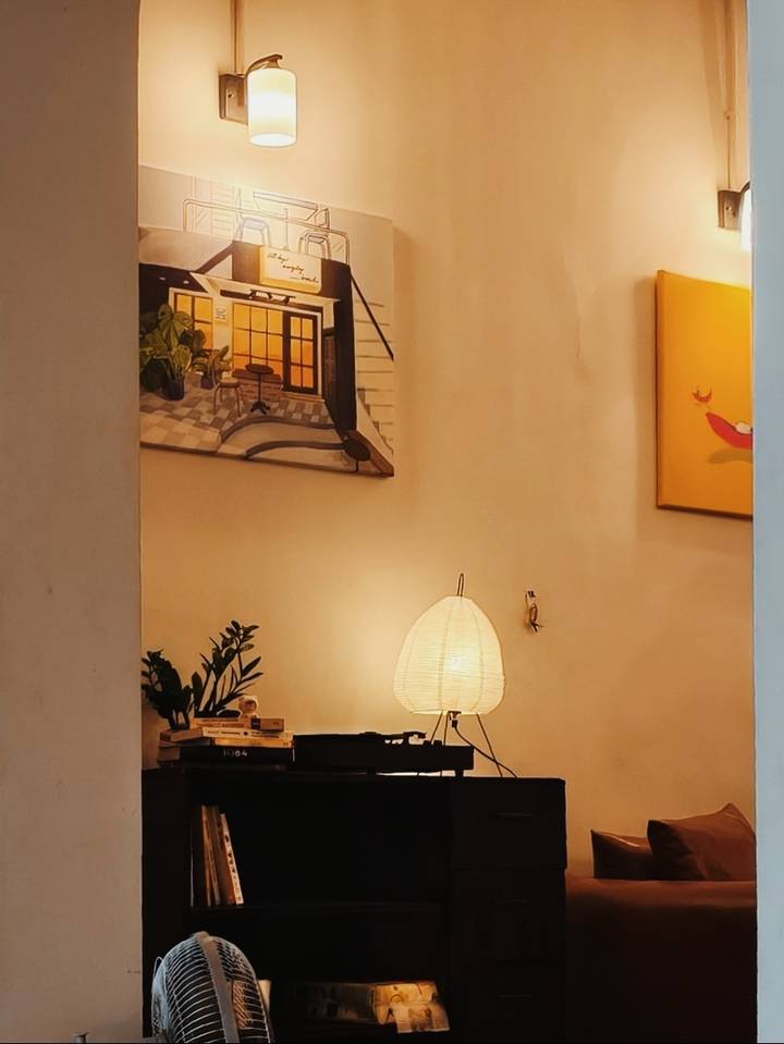 Cozy interior corner with a glowing table lamp, potted plants and wall art creating a warm ambiance.