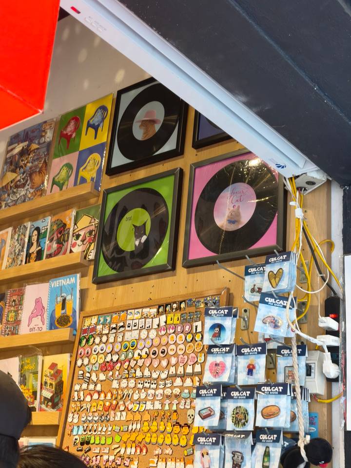 Interior of a quirky shop wall displaying framed vinyl records, art prints and souvenir magnets.
